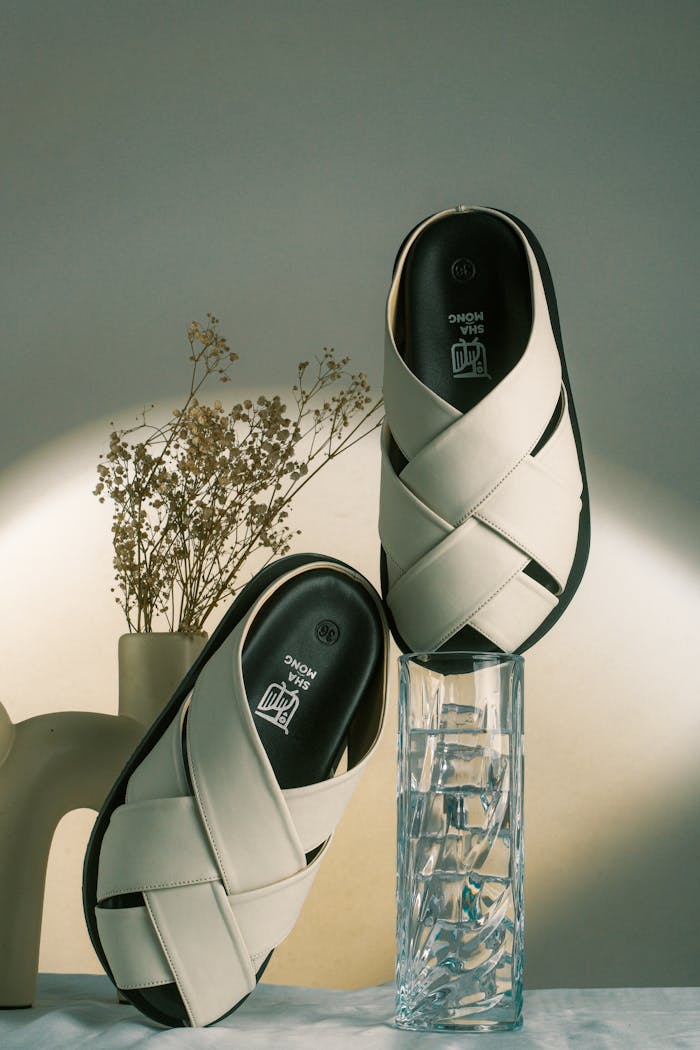 Stylish white sandals creatively displayed with artistic lighting.
