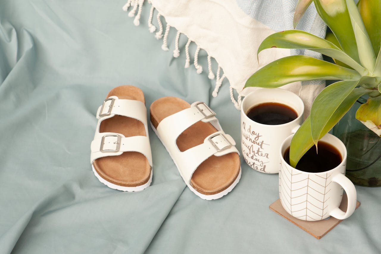 services-04 Flat lay scene with white sandals, coffee mugs, and a plant, perfect for summer relaxation.