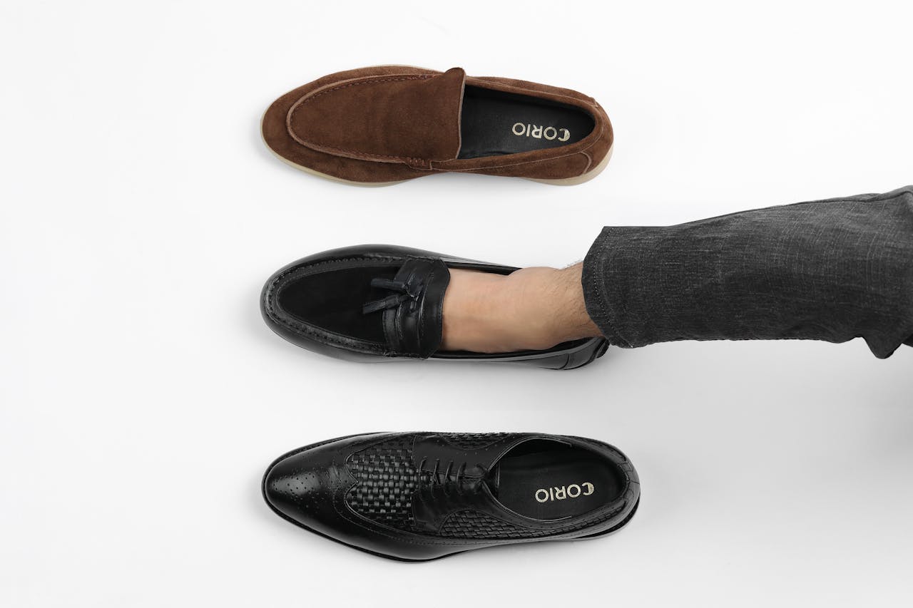 Top view of three men's leather shoes in different styles on white background.