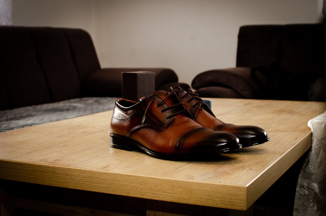Stylish brown leather shoes placed on a wooden table in a cozy indoor setting.