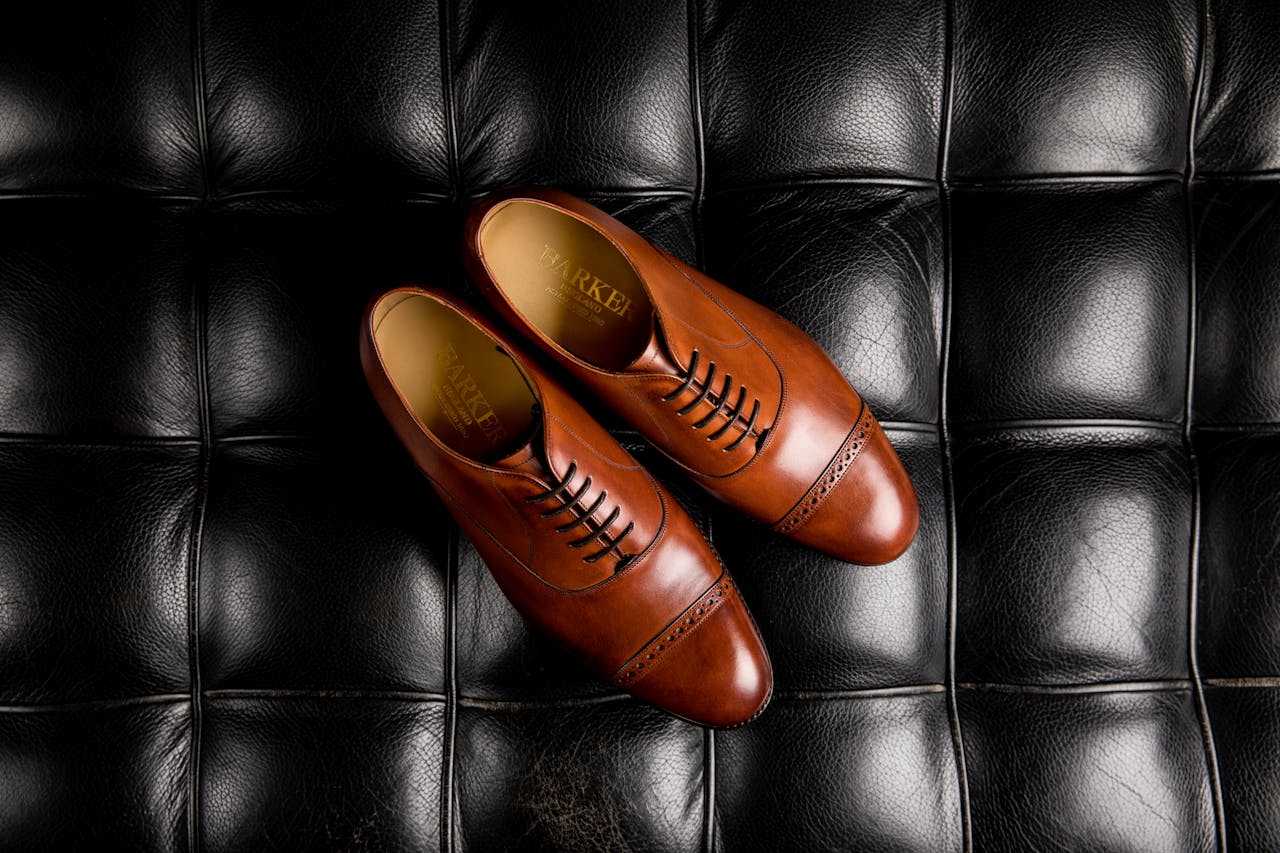 Pair of elegant brown leather oxford shoes displayed on a quilted black leather surface.